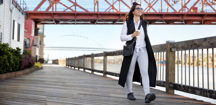 a person walks with a cup of coffee in their hand along a boardwalk